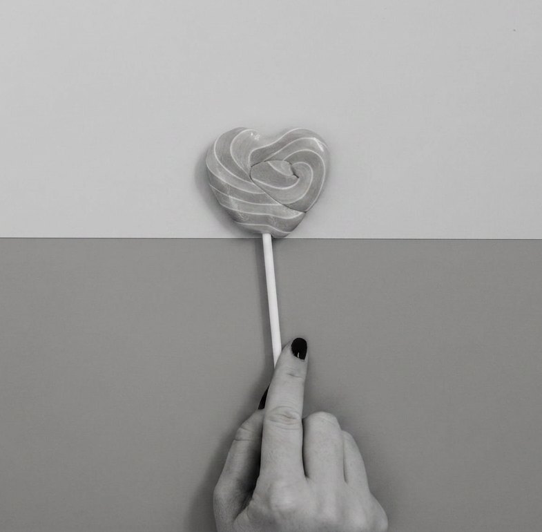 woman hand holding lollipop on two colored background